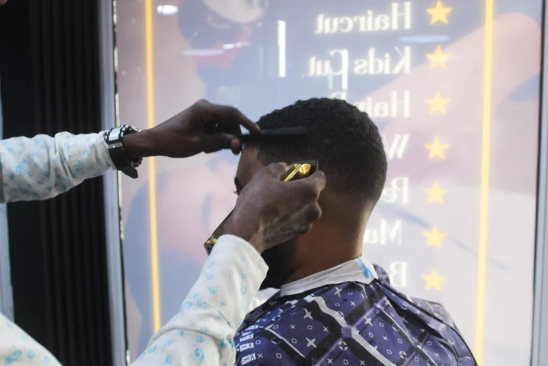 Barber shaping a client's hairline with a comb and clippers