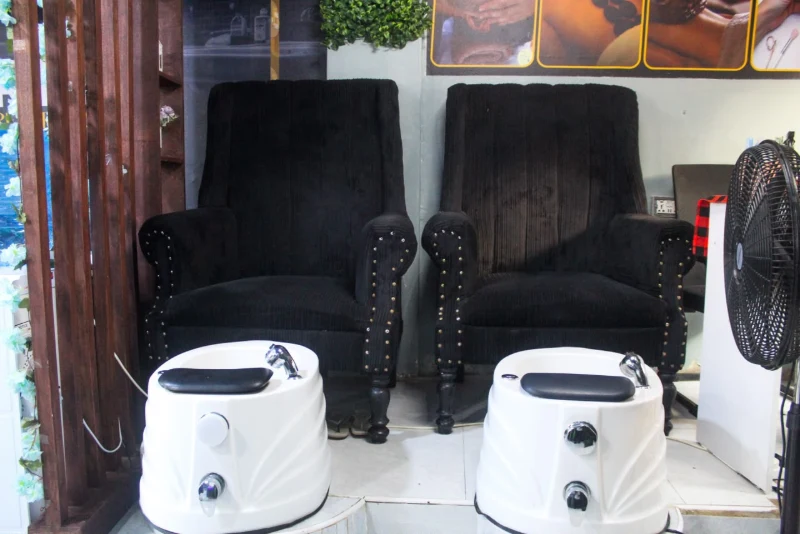 Two black pedicure chairs with white foot basins