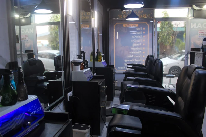 Barber chairs lined up beside a mirror, with a sterilizer ready at the station