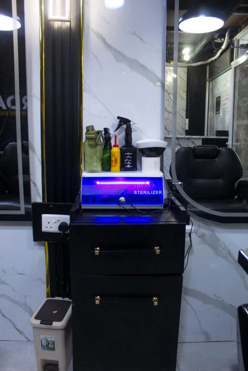 Barber station with a sterilizer and bottles on a black trolley